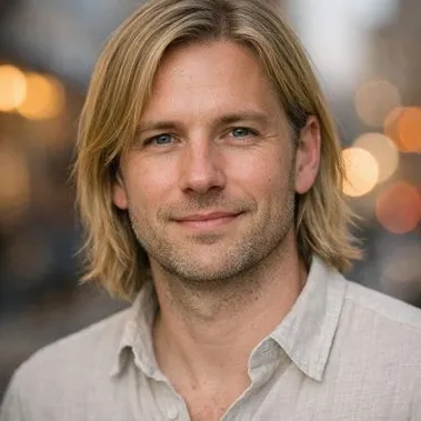 Man in his late 30s, blonde shoulder-length hair, grey-blue eyes, relaxed expression